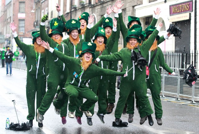 Parade goers dressed as leprechauns jump
