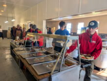 People serving themselves at cafeteria buffet