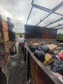 Workers loading trash into industrial dumpster