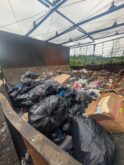 Dumpster filled with black garbage bags