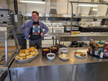 Smiling person behind breakfast buffet of biscuits