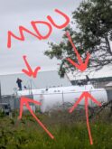 Workers on white storage tank with red markings