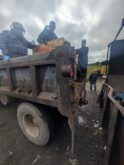 Workers handling debris beside rusty dump truck